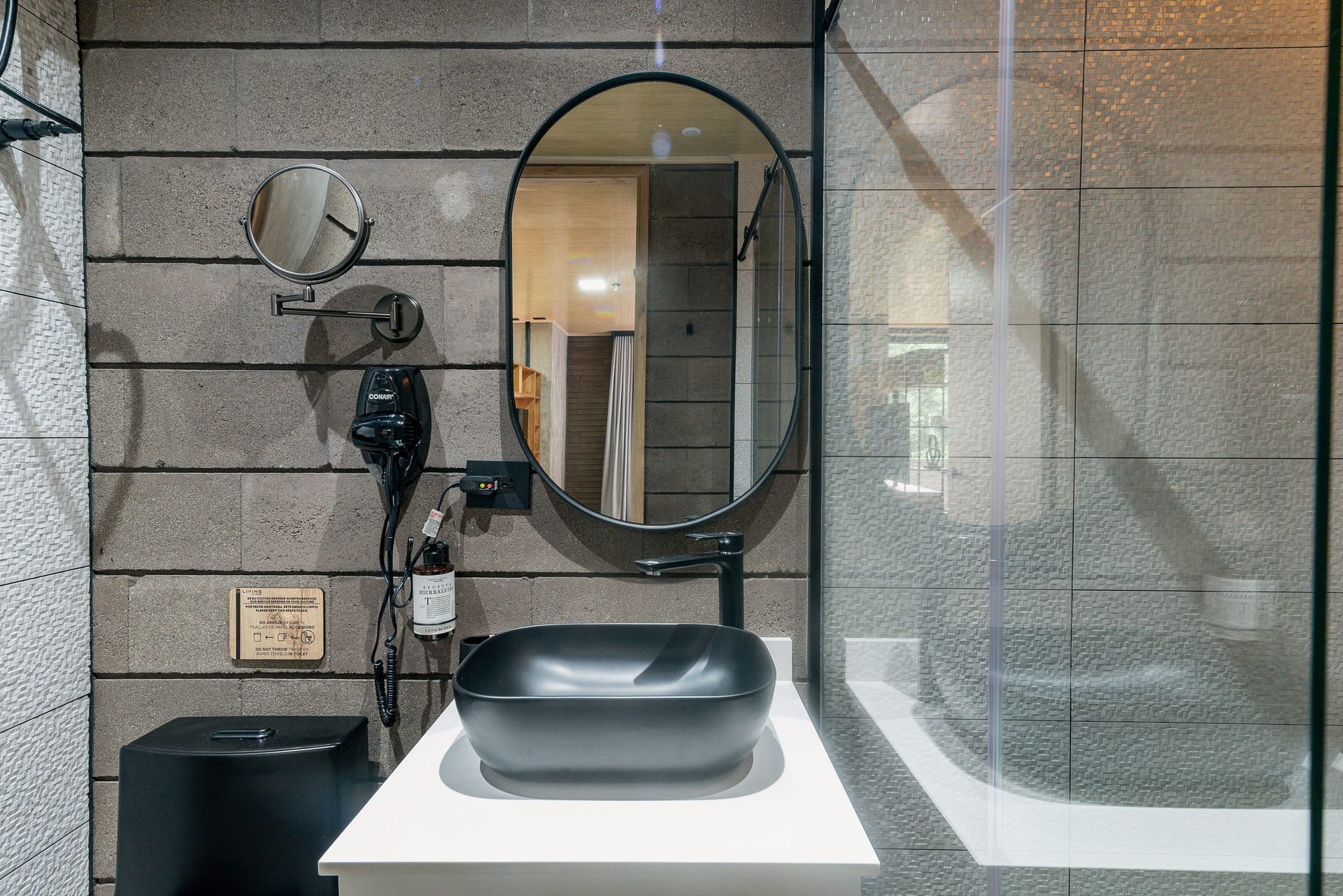 Baño con lavamanos negro y espejo ovalado