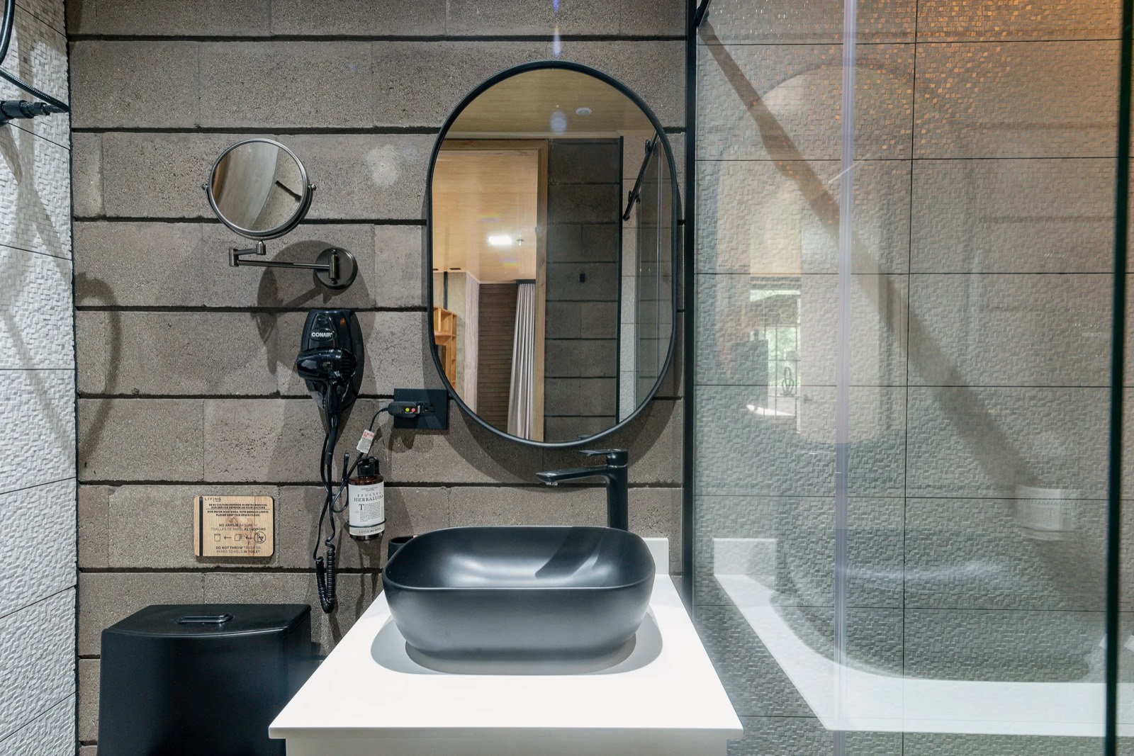 Baño con lavamanos negro y espejo ovalado